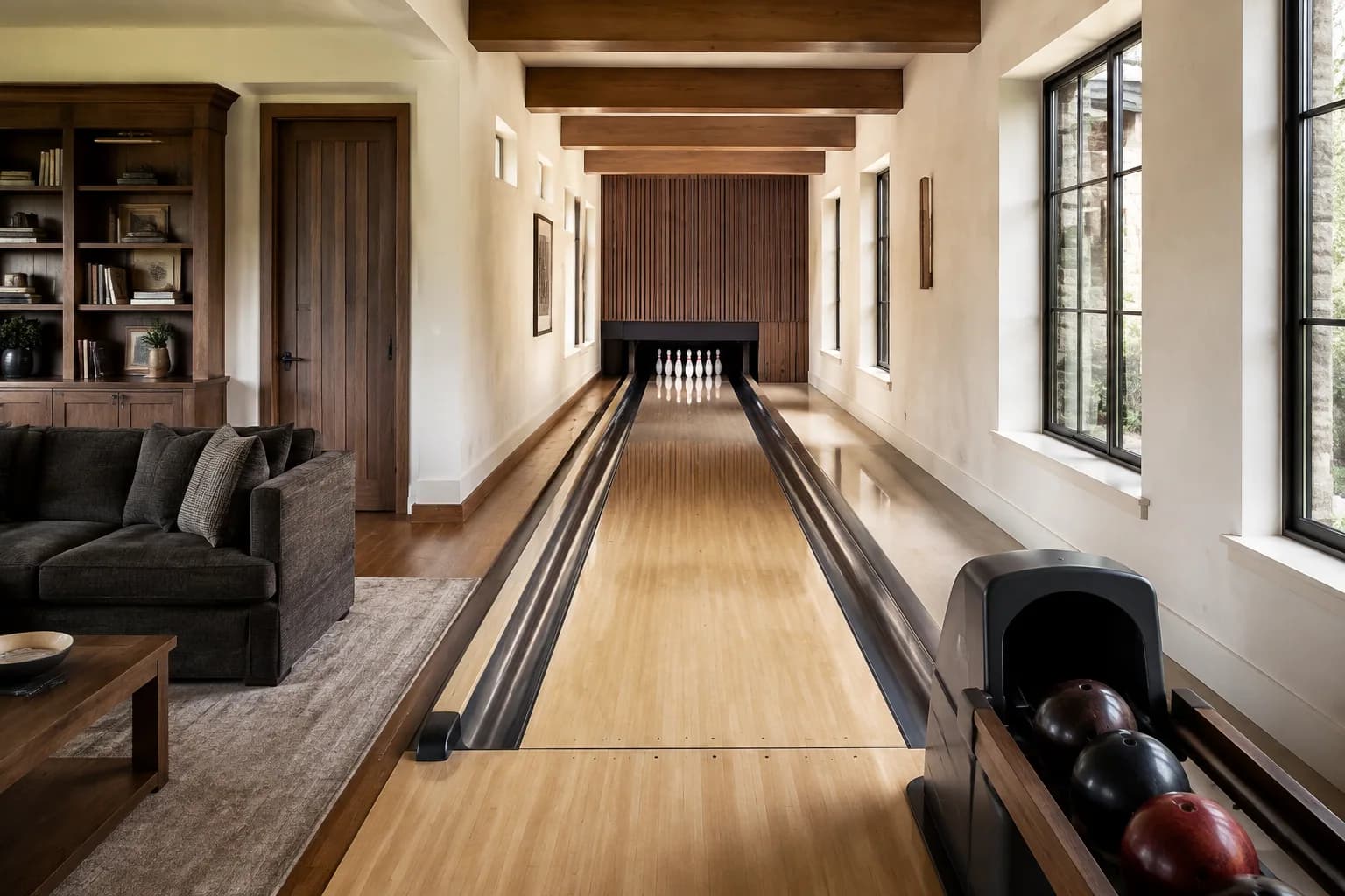 A maple bowling lane beside a walnut library and a soft charcoal sofa